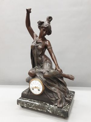 statue d'une femme assise sur un rocher, tenant une horloge à la main