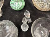 many glass pieces on a table with a green vase in the background