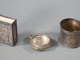 three pieces of silverware including a book, a cup, and a spoon