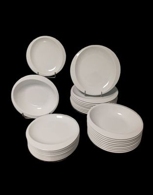 Plusieurs assiettes blanches sont empilées les unes sur les autres sur un fond noir.