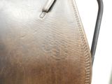 a close up of a brown leather bag on a chair