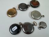 five different types of pocket watches on a white table