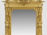 un miroir à cadre doré surmonté d'une statue