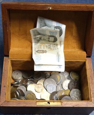 a wooden box full of coins and money sitting on the floor