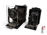 two old cameras sitting next to each other on a white surface