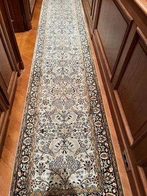 une photo d'un couloir avec un long tapis au sol