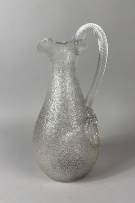 a glass pitcher with a rope handle on a table
