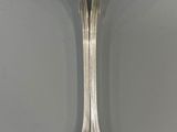 a silver spoon with a bird shaped handle on a gray surface