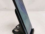the back of a black cell phone on a stand on a white surface