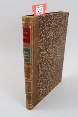 un vieux livre posé sur une table blanche, à côté d'un autocollant rouge