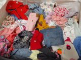 a suitcase full of clothes and clothes sitting on a bed