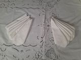 deux serviettes pliées posées sur une nappe blanche