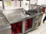 un homme debout dans une cuisine, avec beaucoup de vaisselle sur le plan de travail
