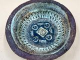 a blue bowl with a design on it sitting on a table