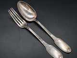 two silver spoons and a fork on a black background