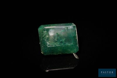 un gros plan d'une émeraude verte posée sur une surface noire
