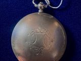 a silver pocket watch on a blue cloth