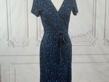 blue and black dress on a mannequin stand in front of a white wall