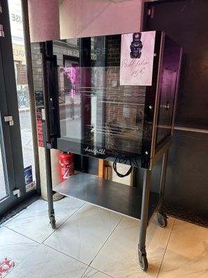 une machine sur laquelle est apposée une affiche, devant une vitrine