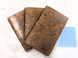 trois portefeuilles en cuir marron posés sur une table blanche