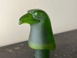 une figurine d'oiseau verte posée sur une table noire