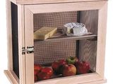 une armoire en bois avec une porte vitrée, dans laquelle se trouvent des pommes et du fromage