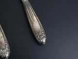 pair of silver plated spoons on a black surface