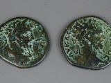 two ancient roman coins, one of which has a face and the other of which has a head