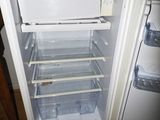 an open refrigerator that is sitting on a wooden floor