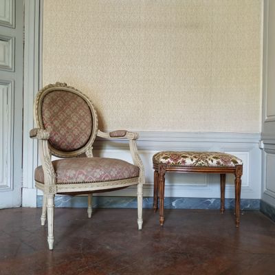 un fauteuil et un pouf dans une pièce dont l'un des murs est recouvert de papier peint