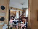 un miroir posé sur une table dans une pièce où il y a des tableaux accrochés au mur