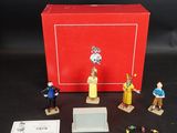 figurines représentant des personnes debout devant une boîte rouge posée sur une surface noire