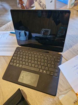 un ordinateur portable posé sur une table recouverte de papiers