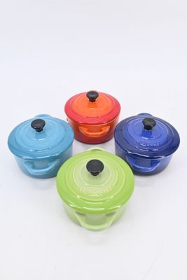 multicolored cast iron dutch ovens on a white background