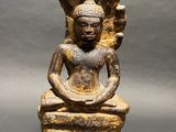 an old statue of a buddha sitting on a wooden base