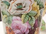 a vase with flowers painted on it sitting on a table