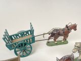 several figurines of horses pulling a wagon with a man on it