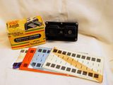 une photo en noir et blanc représentant un vieil appareil photo et une boîte de cassettes