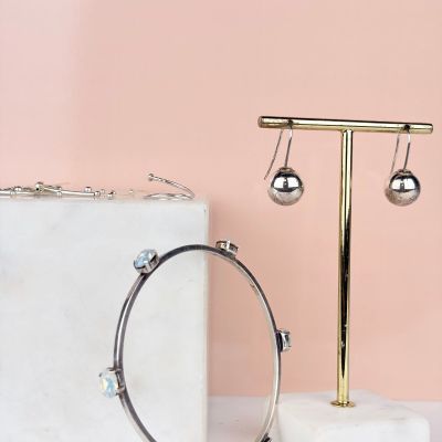 un gros plan sur une paire de boucles d'oreilles posées sur un présentoir à côté d'un bloc de marbre