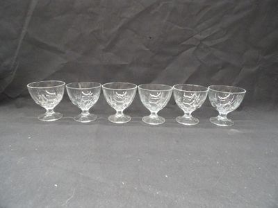 six glass goblets lined up in a row on a black background