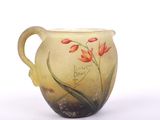 a glass pitcher with flowers painted on it on a white surface
