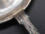 a silver spoon with a handle on a black surface