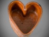 brown ceramic heart shaped bowl sitting on top of a gray surface