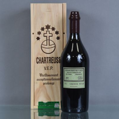 La bouteille de vin se trouve à côté de la boîte en bois sur la table.