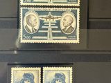 three stamps with portraits of people on them on display in a glass case