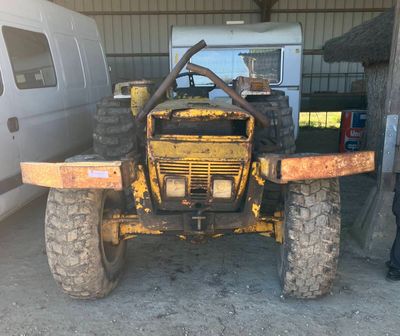 un homme debout à côté d'un tracteur jaune dans un garage