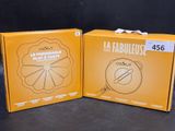 two boxes with a picture of a clock inside of them on a table