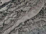 a close up of a gray scarf on a bed
