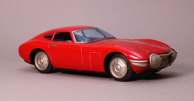 a red toy car that is sitting on a gray surface