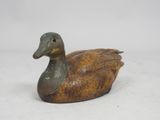 bronze colored duck figurine sitting on a white surface